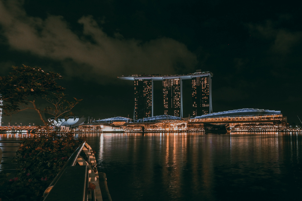 Nighttime view of Marina Bay Sands in Singapore, with its lights reflected across the water.